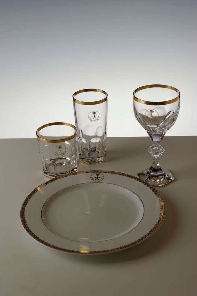 Official table setting with gold-rimmed porcelain, crystal glasses and crest goblet
